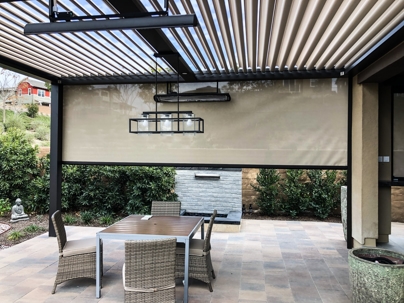 Covered patio with retractable shade, table, chairs, and fireplace.